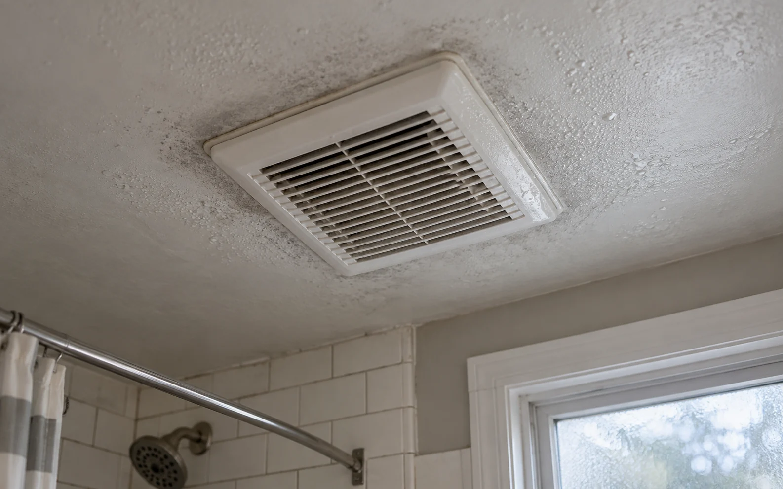Bathroom ceiling exhaust fan grille with grey shadowing on the surrounding paint